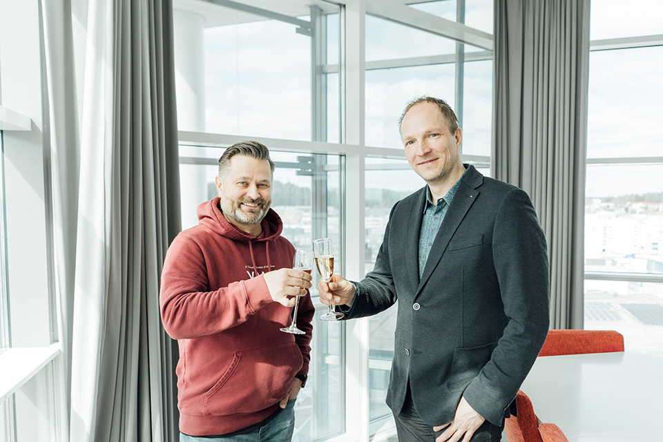 Kuvassa Valu Digitalin perustaja Kari Turunen ja uusi toimitusjohtaja Harri Valkonen nostavat maljat ikkunoiden äärellä.